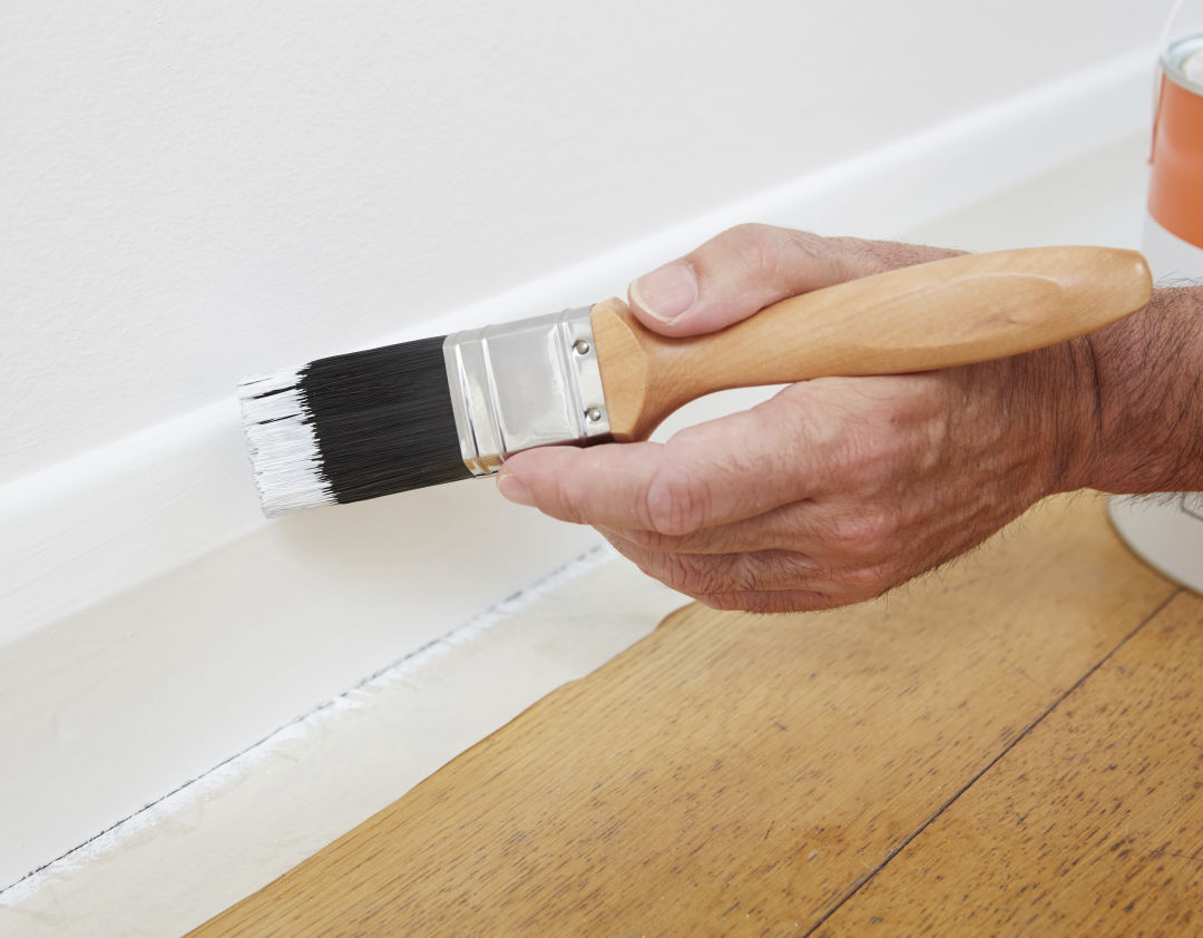 Painting a skirting board with a brush